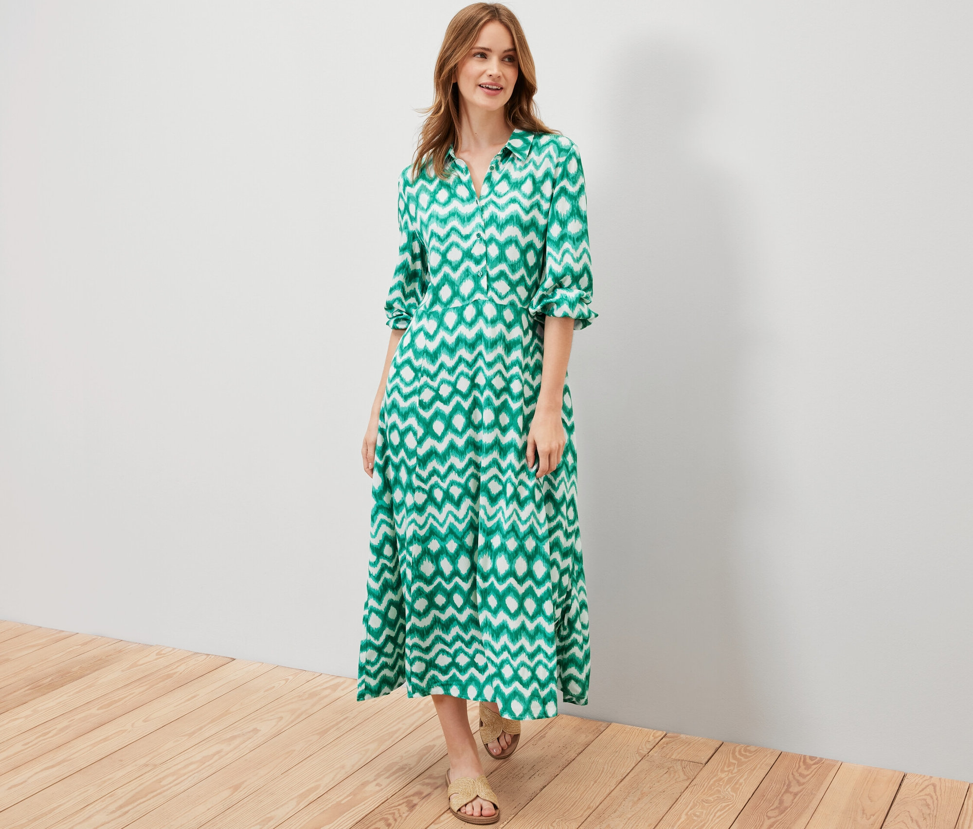 Nő pózol egy zöld, mintás ingruhában.