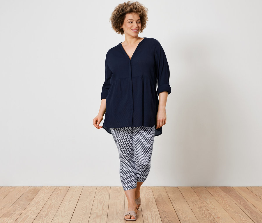 Nő visel egy hosszú tunikablúzt és egy mintás 3/4-es leggingset.