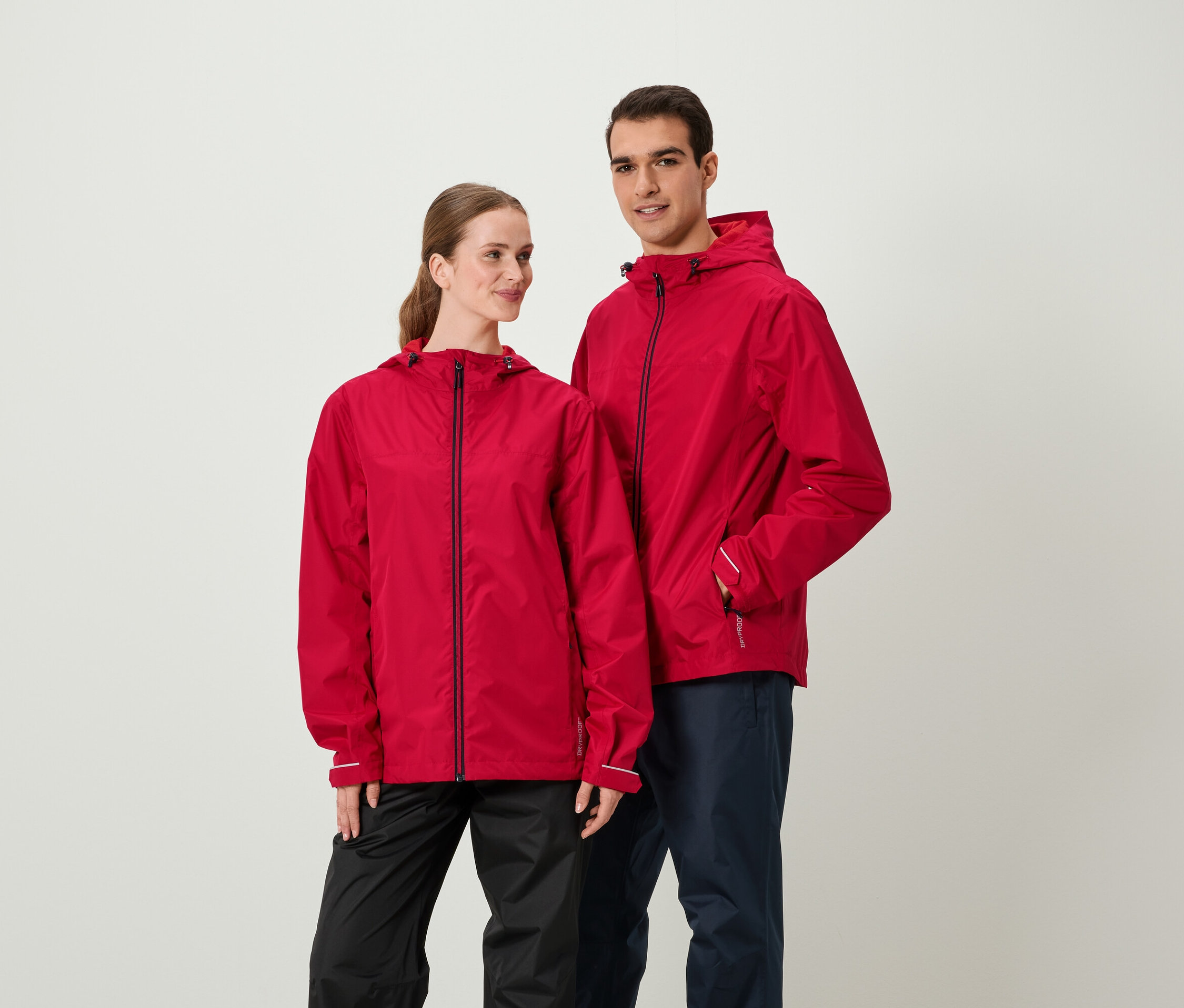 Két ember piros kabátban és sötét nadrágban áll egymás mellett.