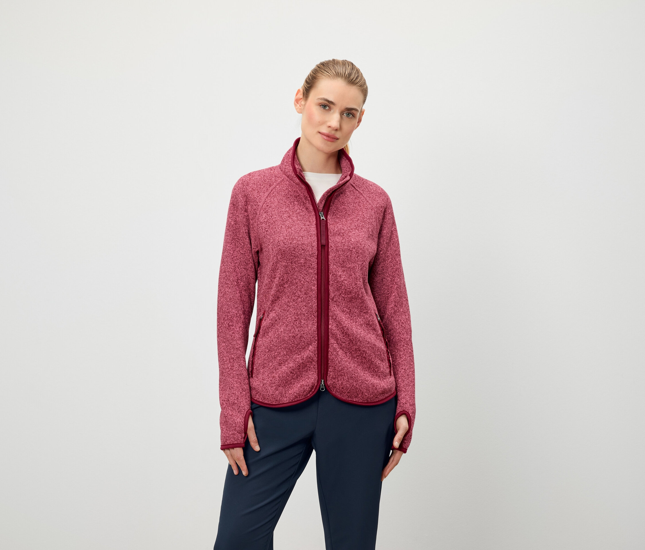 Egy nő hosszú ujjú, cipzáras polár pulóvert és sötétkék nadrágot visel.