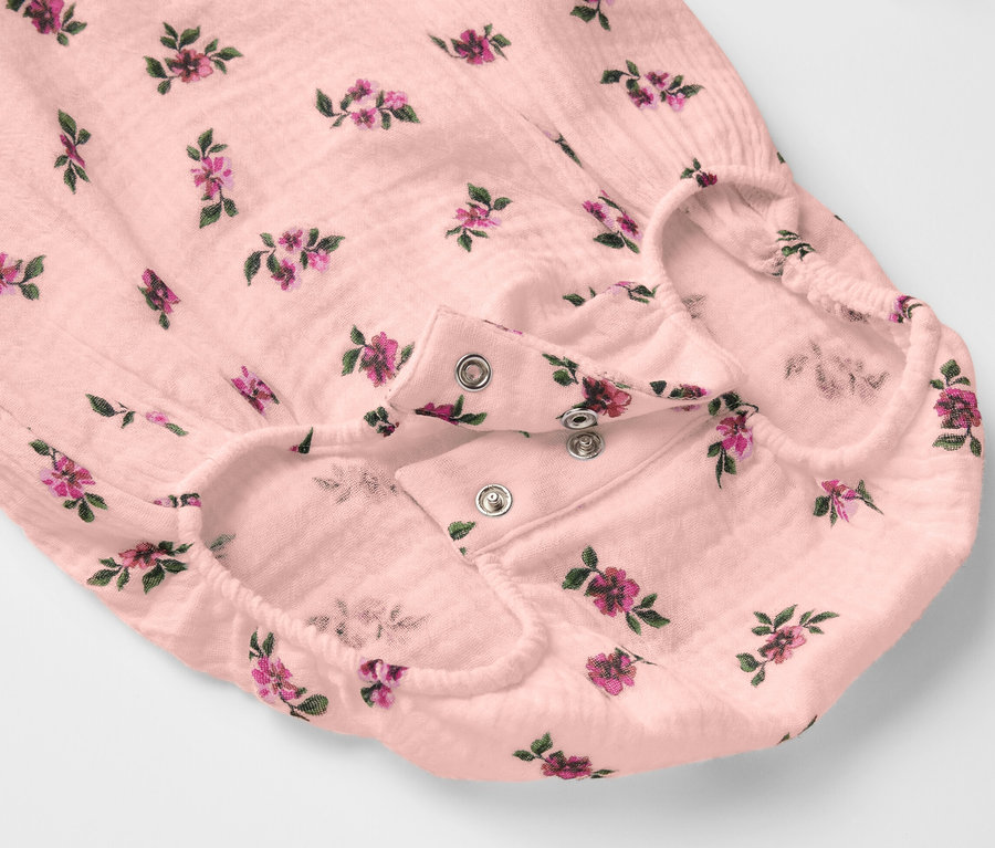 Közelkép egy virágmintás, patentos rögzítésű muszlin bodyról.