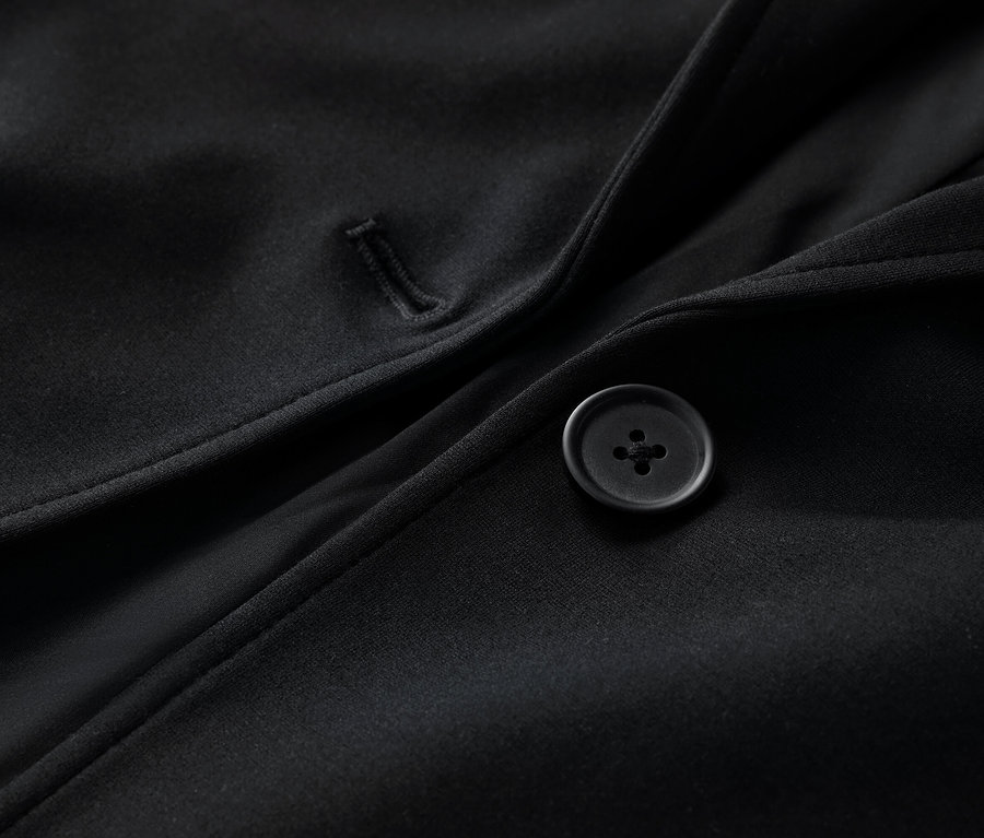 Egy fekete jersey blézer részlete gombbal.