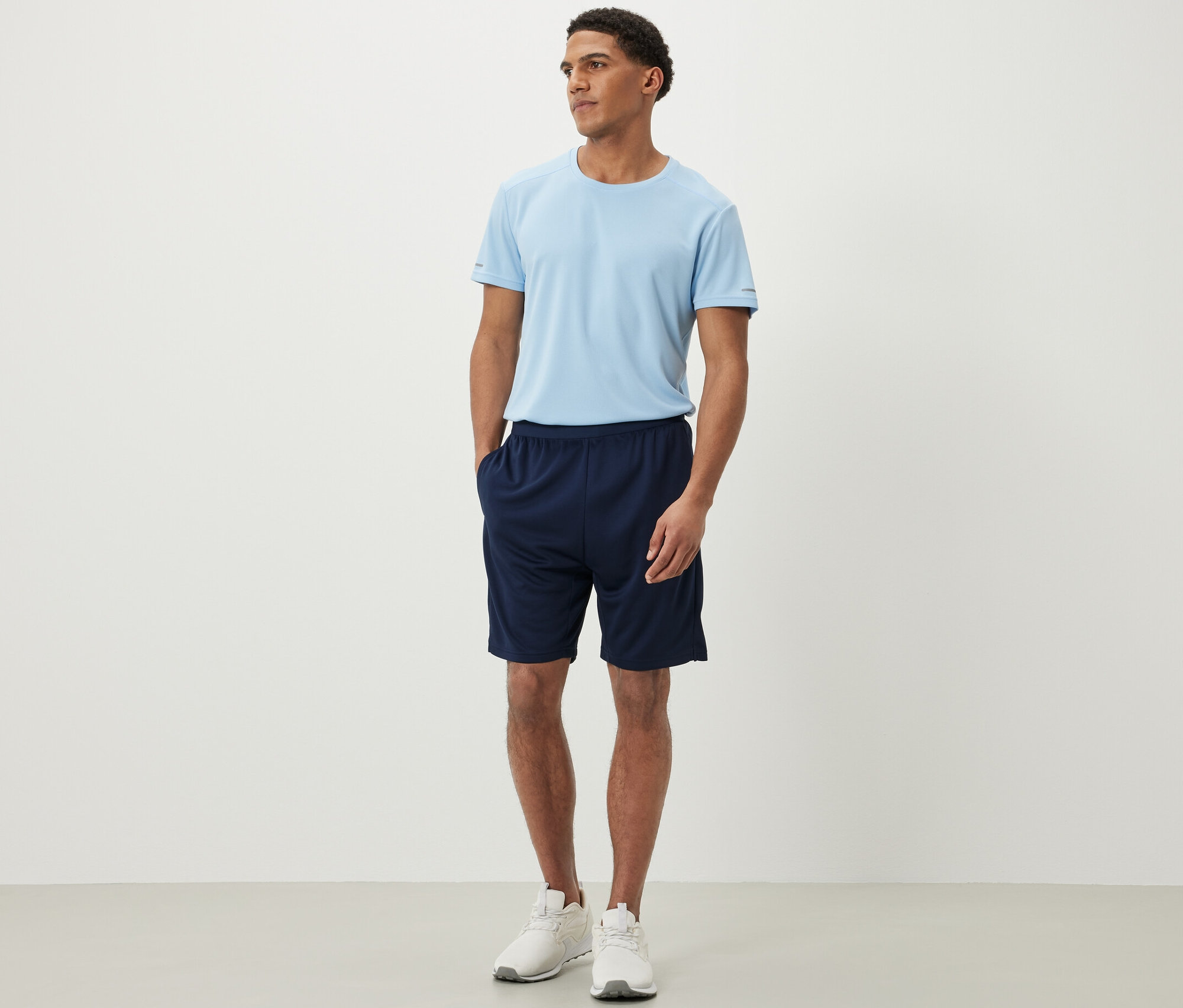 Egy férfi áll sport rövidnadrágban és pólóban.