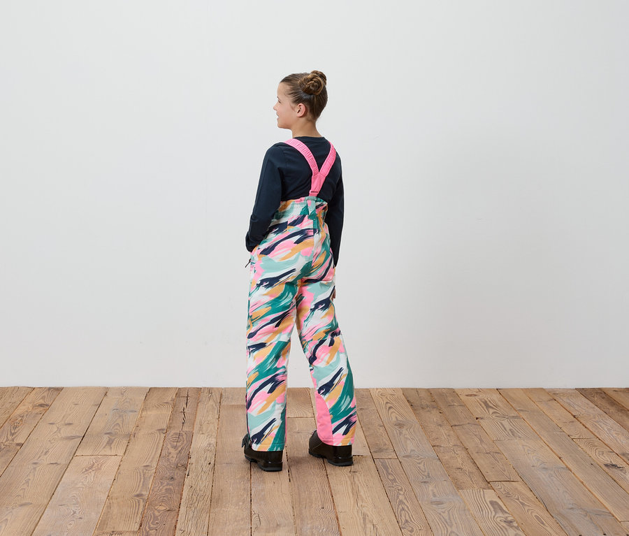 Egy lány színes mintás kantáros nadrágban áll háttal a kamerának.