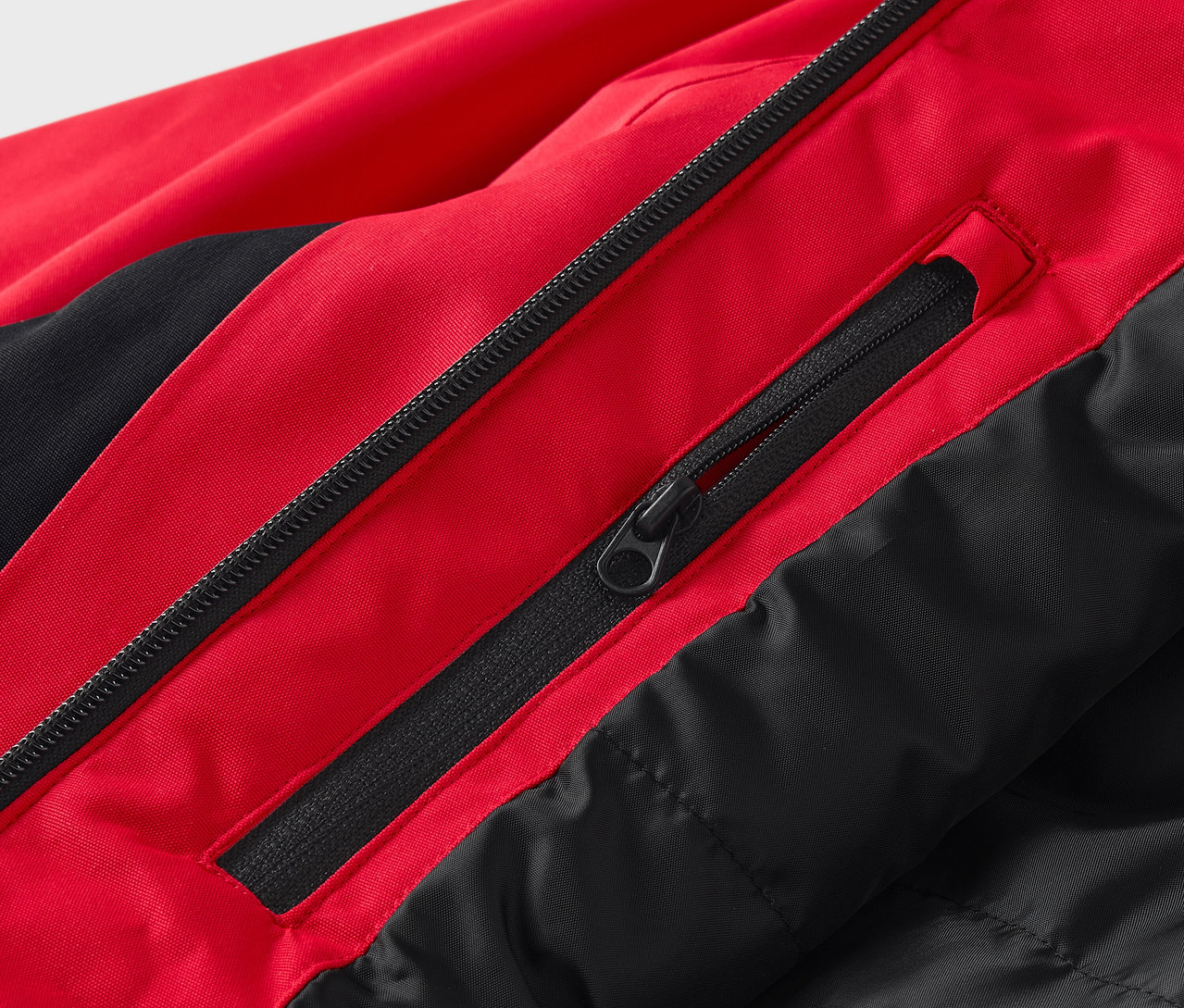 Egy piros-fekete kabát részlete cipzárakkal.