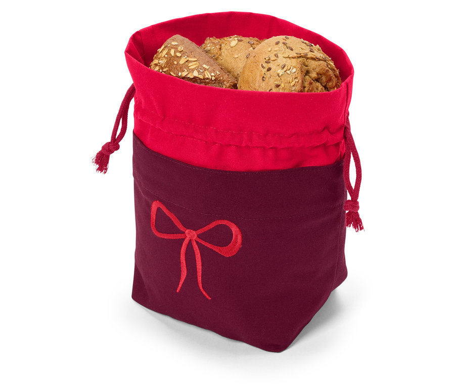 Többmagvas kenyér piros-burgundi színű, húzózsinóros, masni hímzéssel ellátott anyagzsákban.