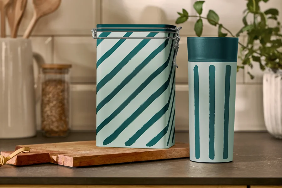 Csíkos kávétartó doboz és Coffee-to-go bögre áll egy konyhaasztalon.