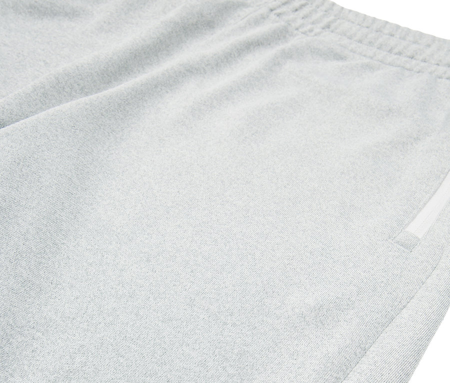 Közelkép egy világosszürke Fila rövidnadrágról, amelynek hasítéka van a szegélyén.