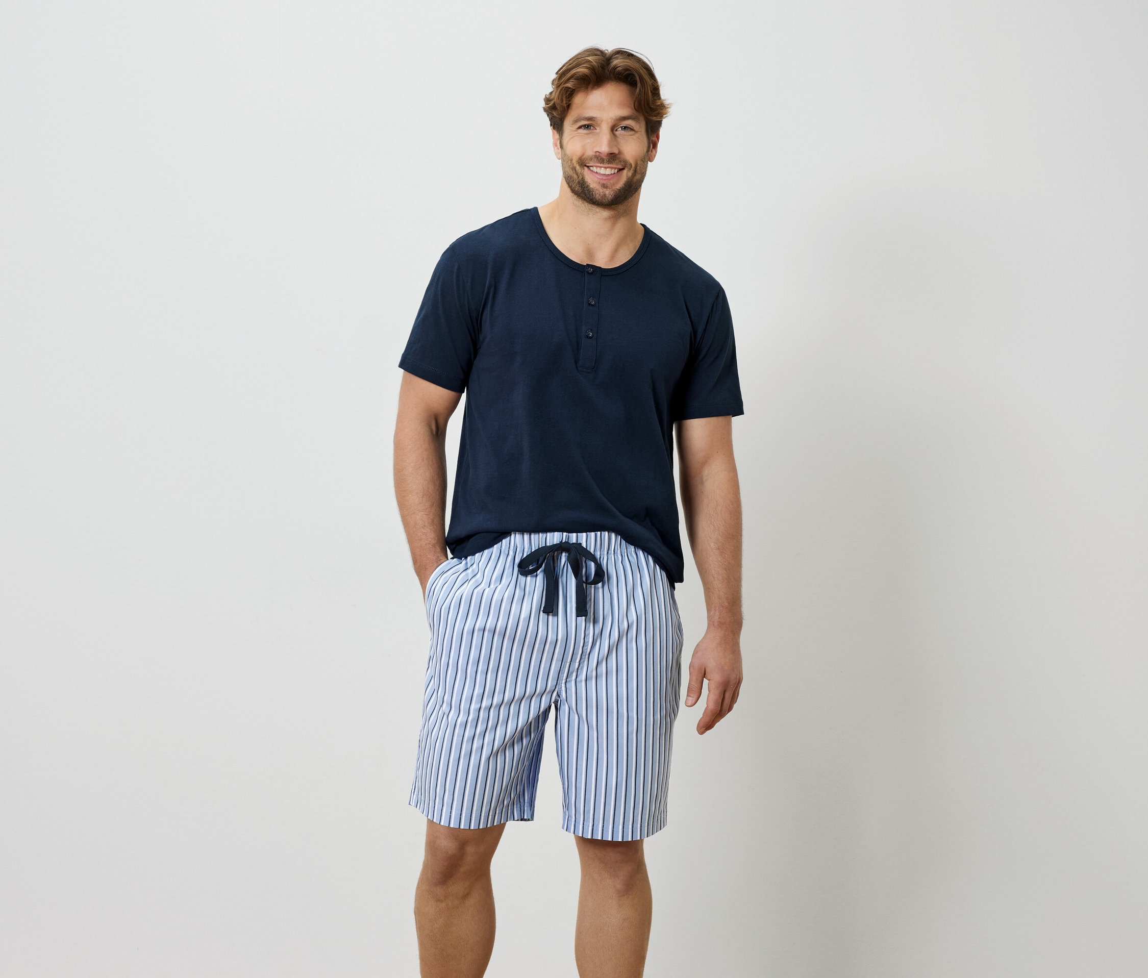 Férfi kék pólóban és csíkos rövidnadrágban.