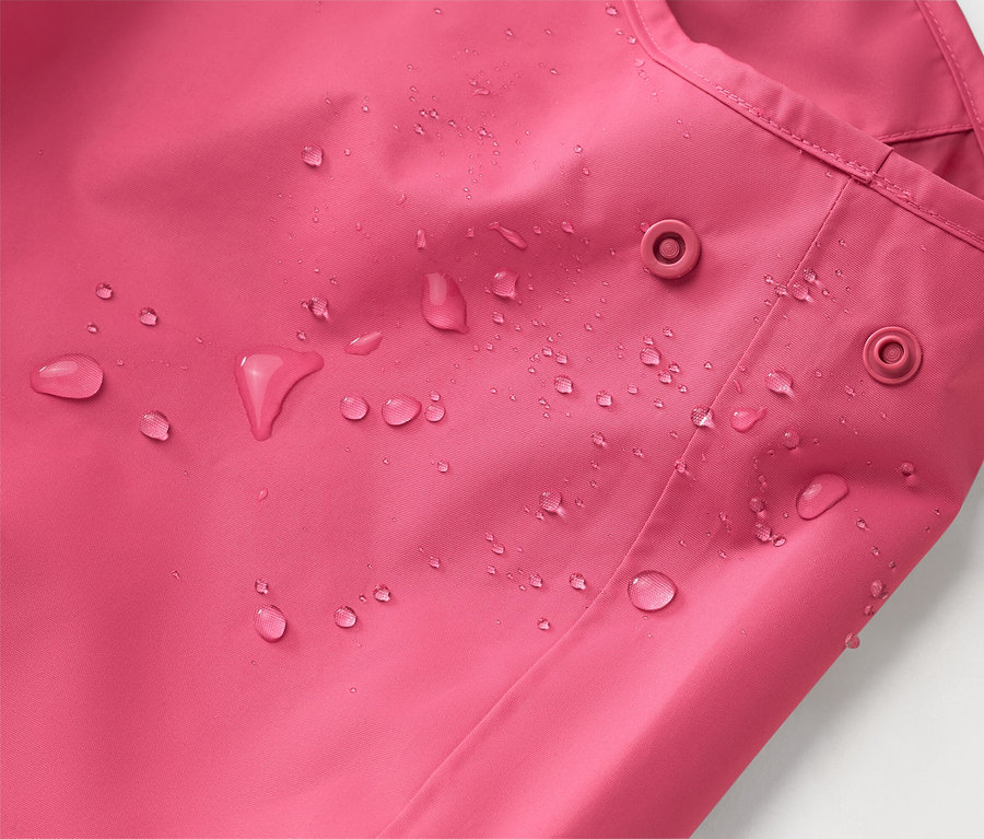 Egy rózsaszín kabát közeli képe vízcseppekkel és két patenttal.