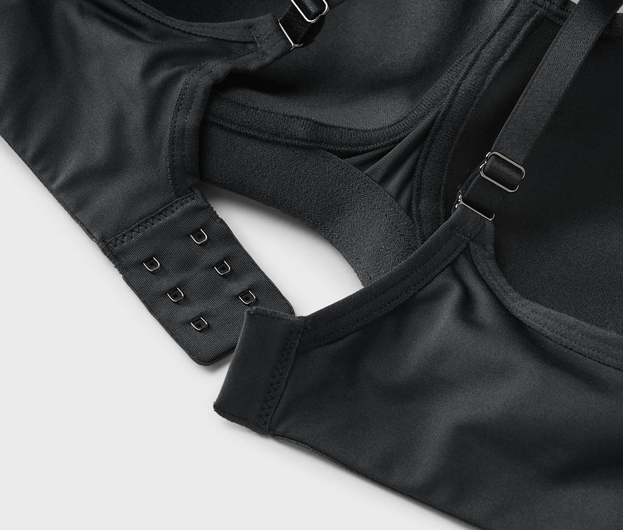 Egy fekete melltartó közeli képe kapcsos zárással és állítható pántokkal.