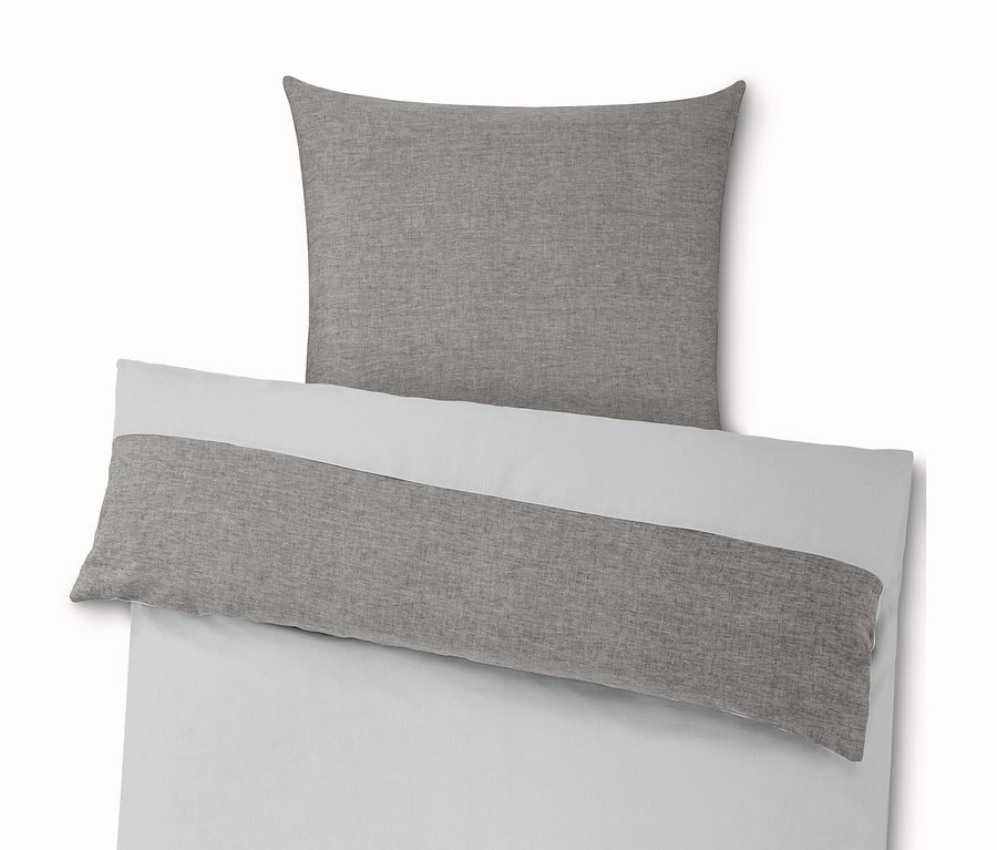 Fehér ágynemű szürke párnával és takaróval.