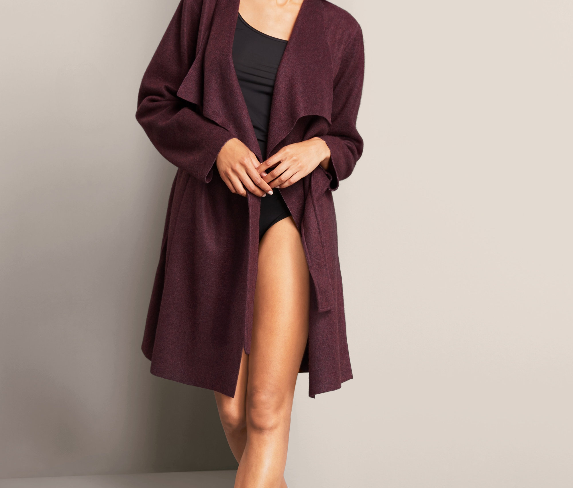 Nő pózol a bordó női puha kardigánban.