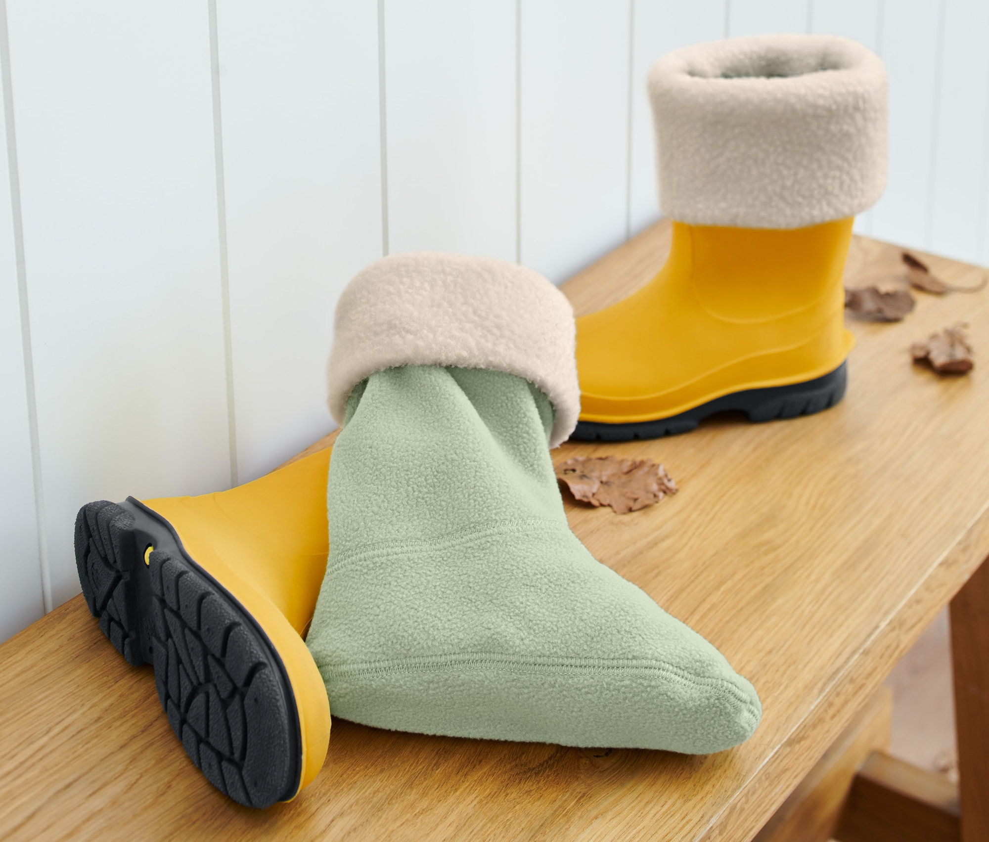 Sárga gumicsizma és világoszöld kisgyerek gumicsizma bélés egy fa padon.