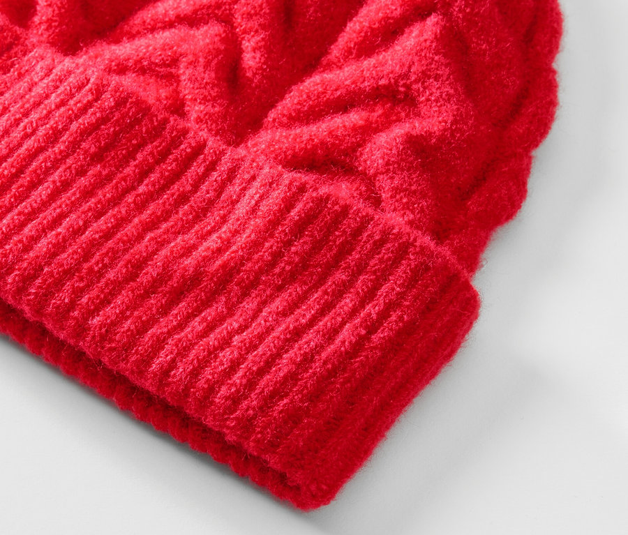 Egy piros, gyapjú kötött női sapka közeli képe.