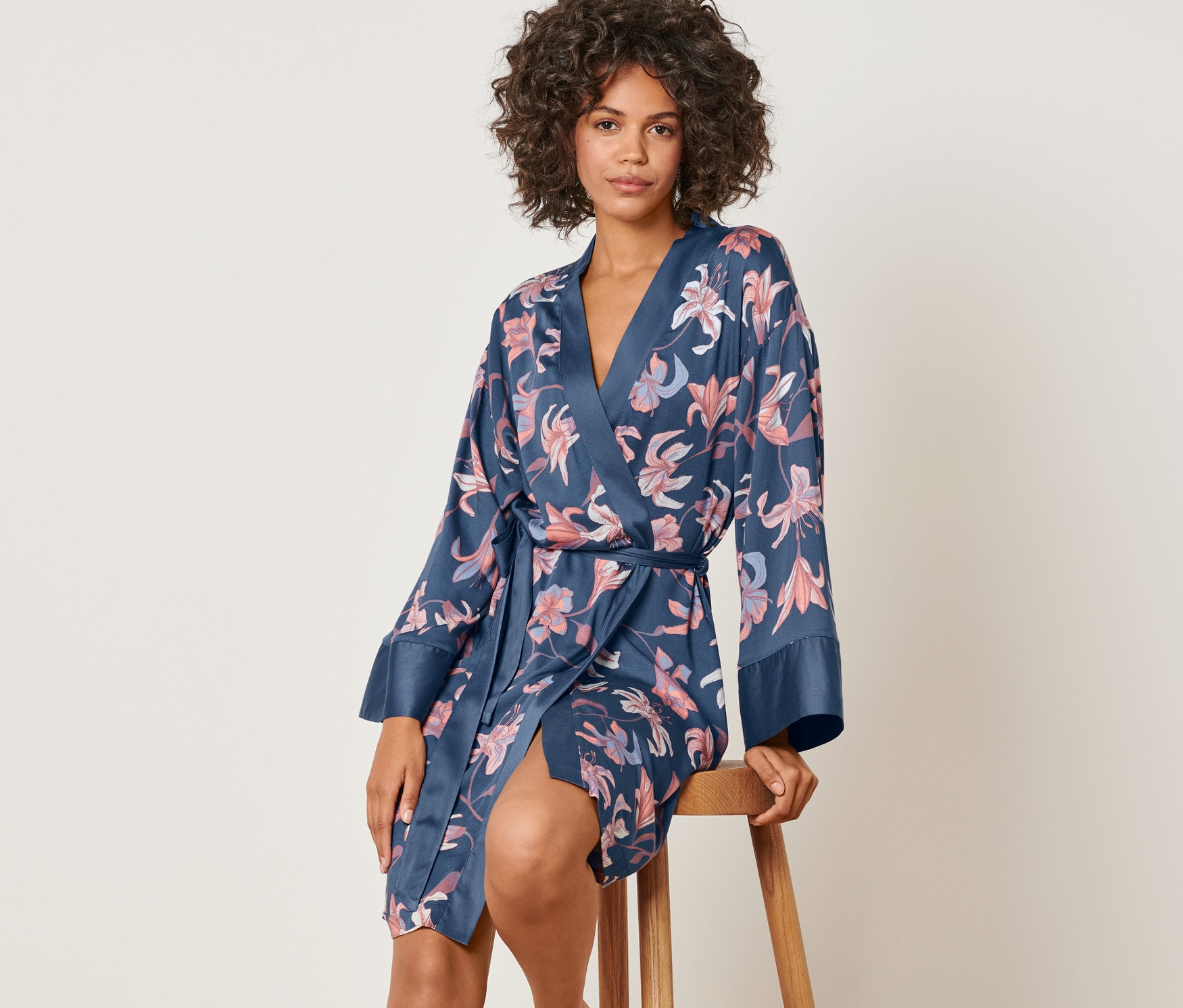 Nő ül egy széken, és egy virágos női kimonót visel.