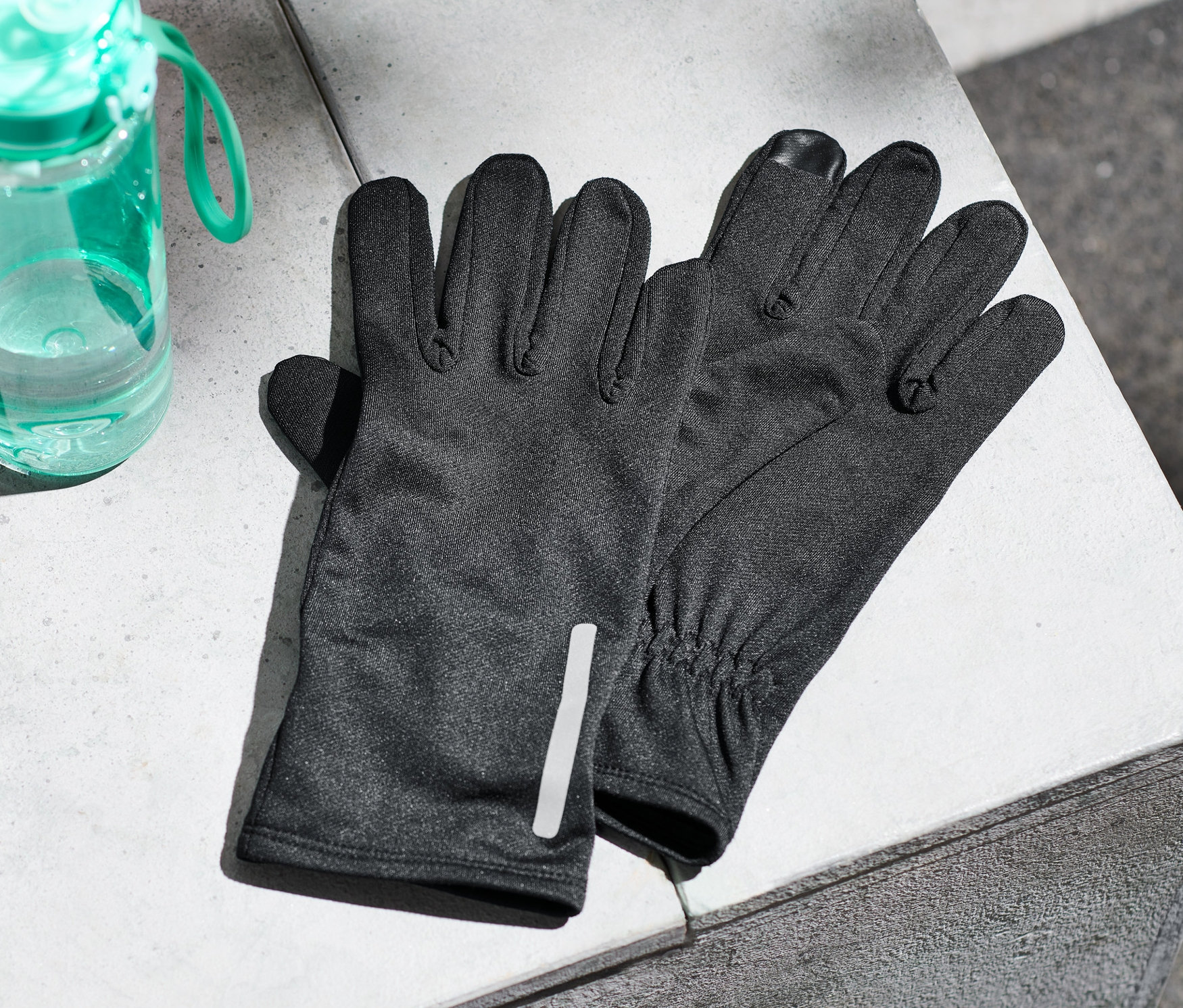 Egy betonfelületen futókesztyű és egy kulacs viz fekszik.