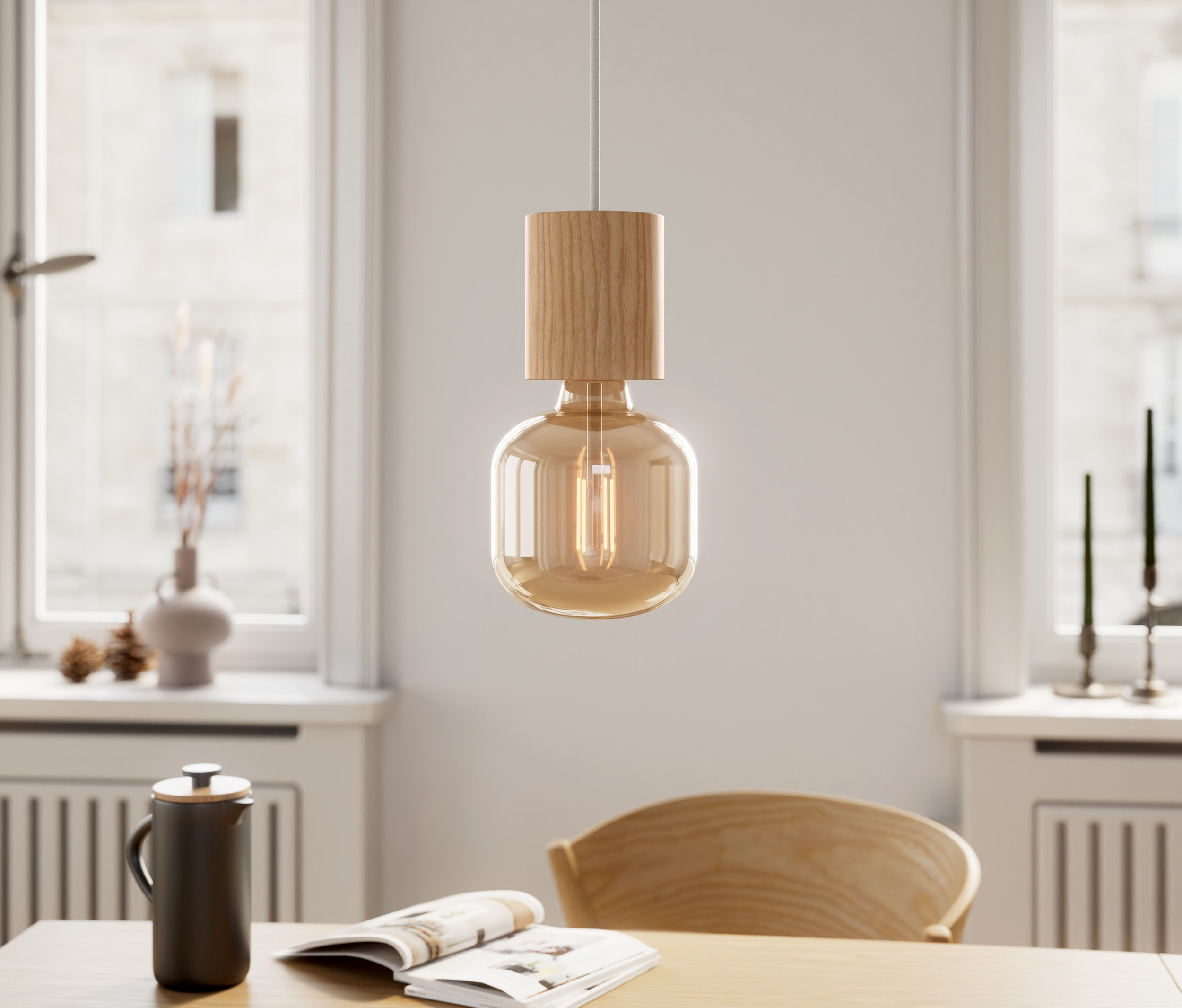 Fa függőlámpa lóg egy asztal fölött, rajta egy könyv és egy csésze.