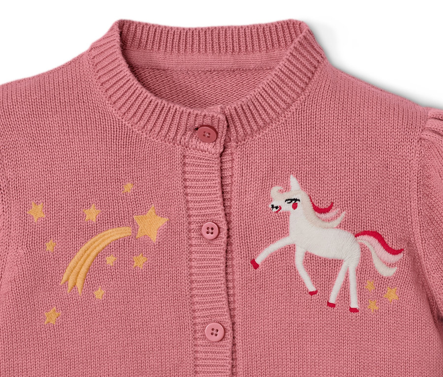 Egy kislány kötött kardigán részlete unikornissal és csillagokkal.