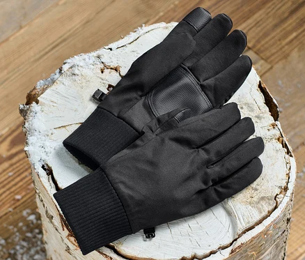 Fekete softshell kesztyűk egy fatönkön.