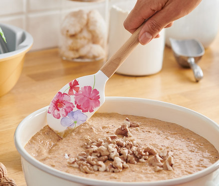 Nő tésztát kever egy szilikon tésztakaparó lapáttal.