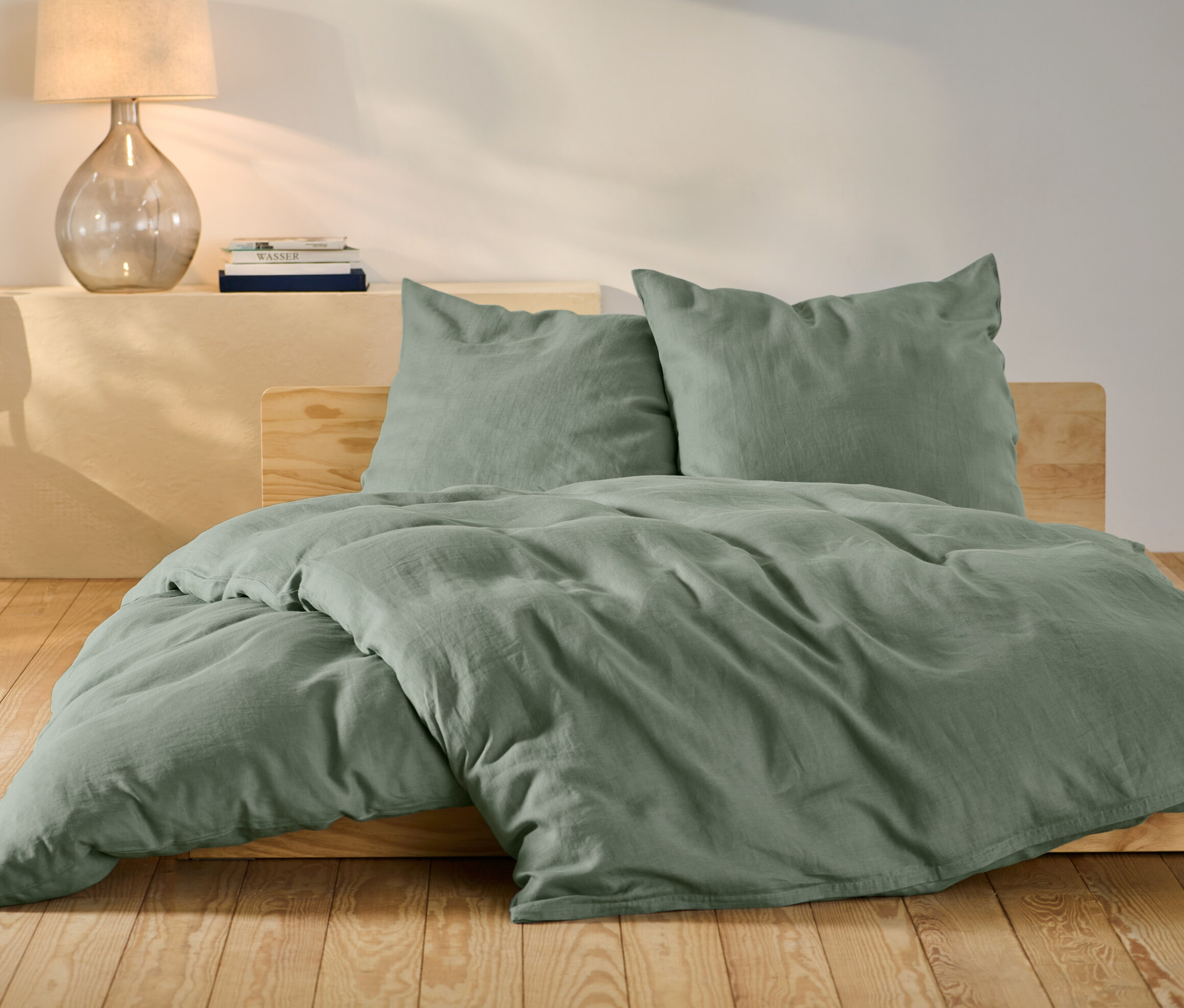 Zöld lenvászon ágynemű normál és extra méretben egy ágyon.