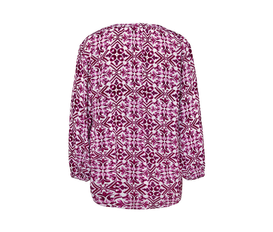 Egy mintás, fukszia színű női 7/8-os ujjú tunikablúz részlete.