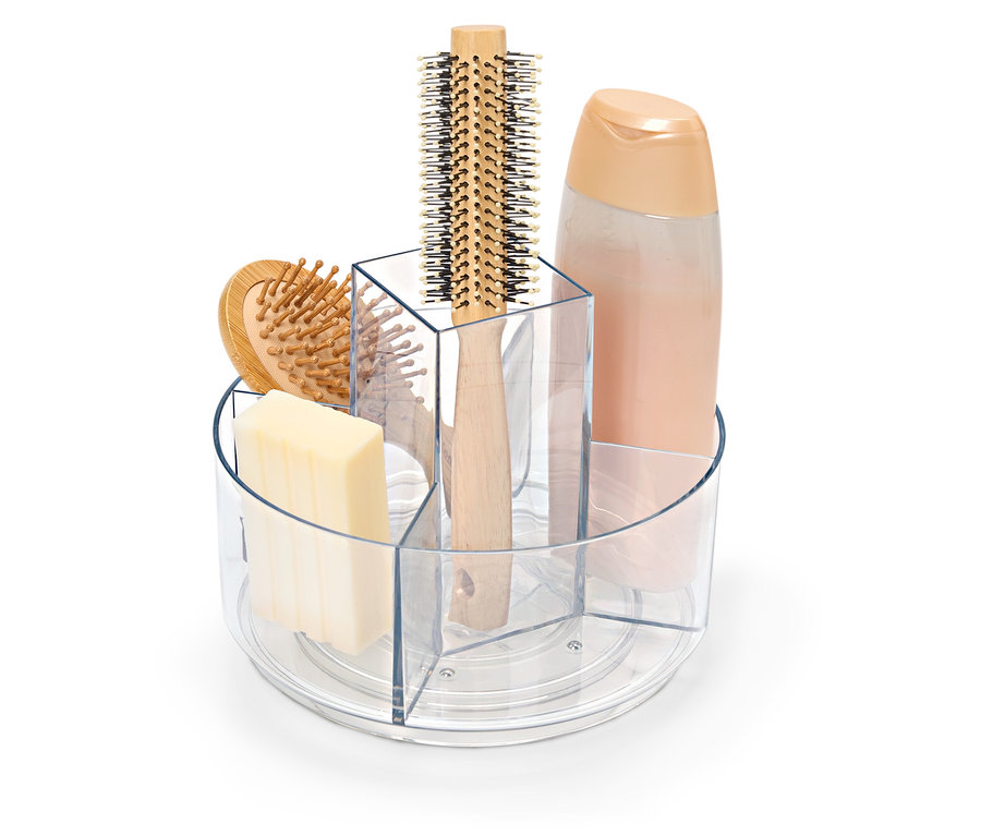 Egy átlátszó, forgatható tartó szappannal, hajkefével és samponos flakonnal.