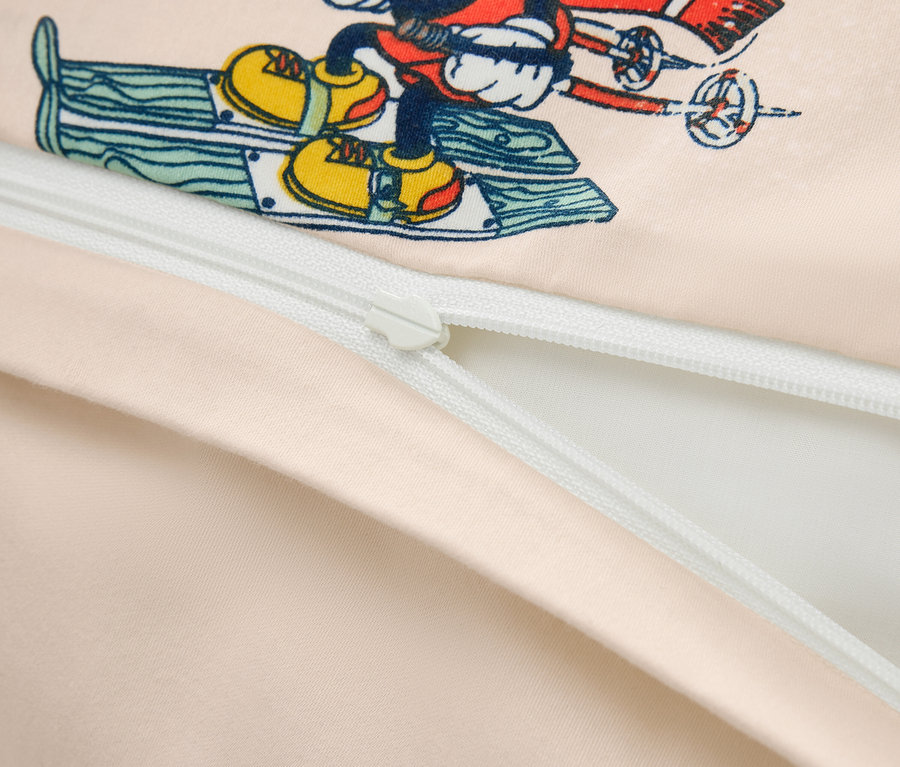 Közelkép egy ágyneműhuzatról, amelyen a síelő Mickey egér látható, részben nyitott cipzárral.