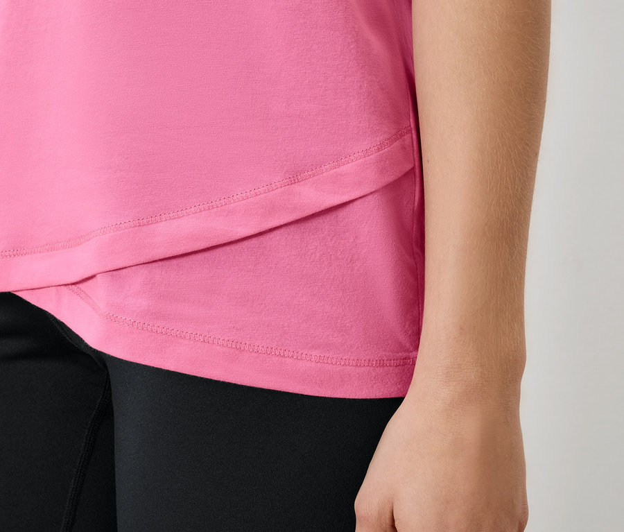 Női rózsaszín póló és fekete leggings részlete.