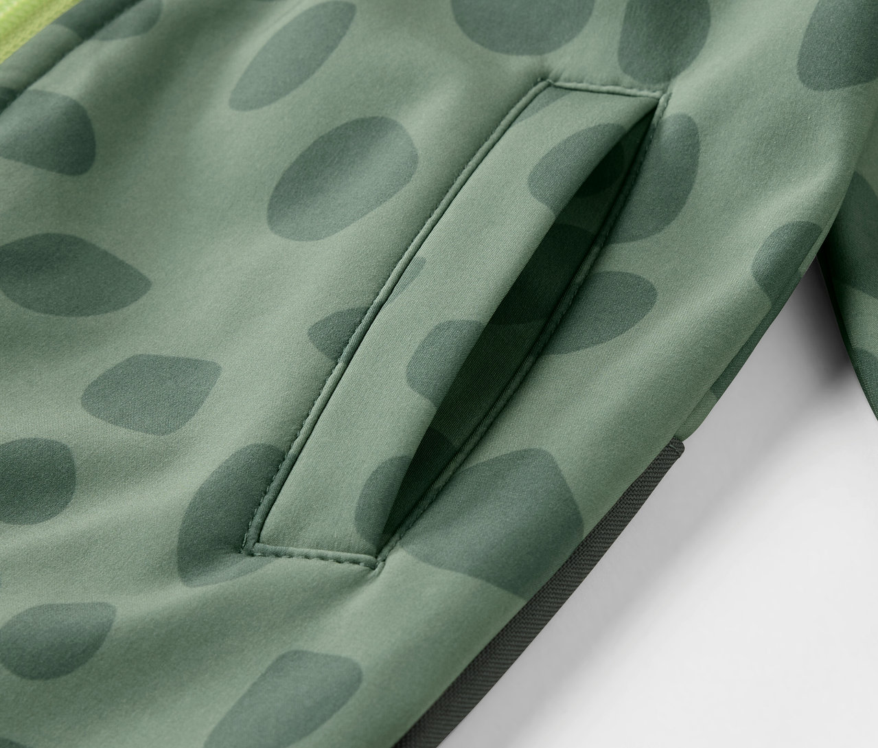 Egy mintás, zsebes gyermek softshell kezeslábas részletének közeli képe.