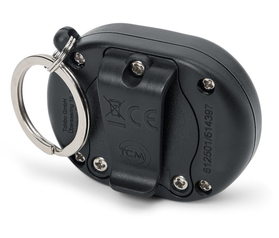 Egy fekete digitális lépésszámláló hátuljának részletes képe, kerek, ezüst színű kulcstartóval.