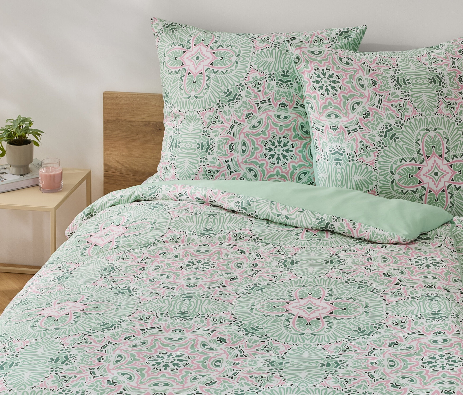 Zöld, normál méretű mikroszálas ágynemű virágmintával egy ágyon.