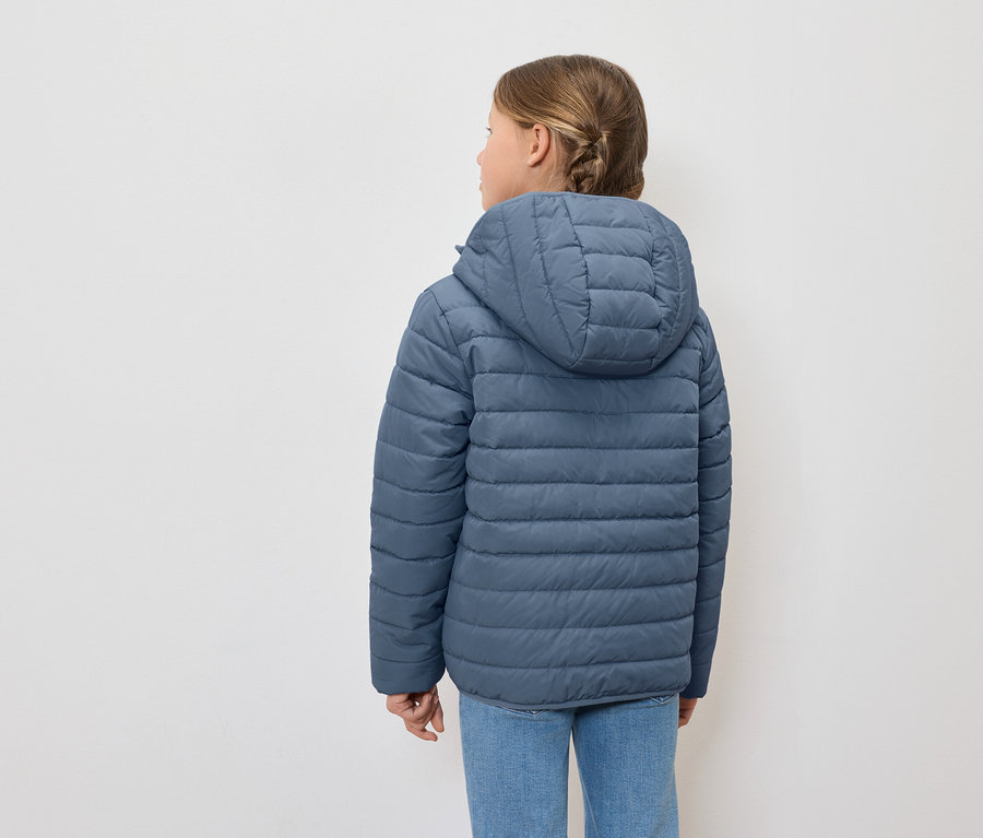 Hátulról látható lány kék, kapucnis pehelykabátot és kék farmert visel.