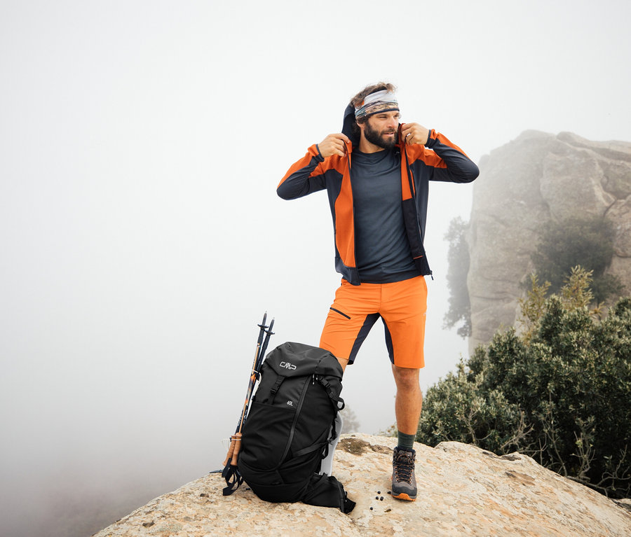 Férfi áll a sziklán egy CMP HAVRE túrahátizsákkal, 40 literes. A túrabotok a hátizsáknak vannak támasztva.
