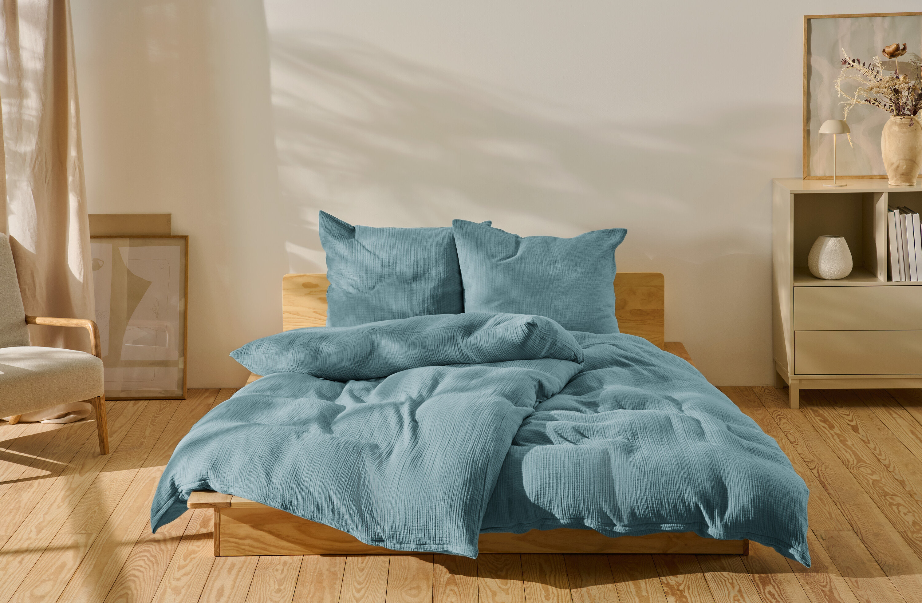 Kék, normál méretű és extra méretű muszlin ágynemű egy ágyon.