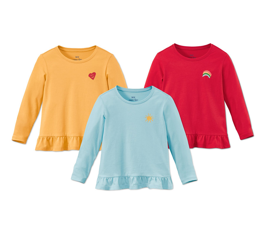 Három bio pamut póló: egy sárga szív mintával, egy kék nap mintával és egy piros szivárvány mintával.