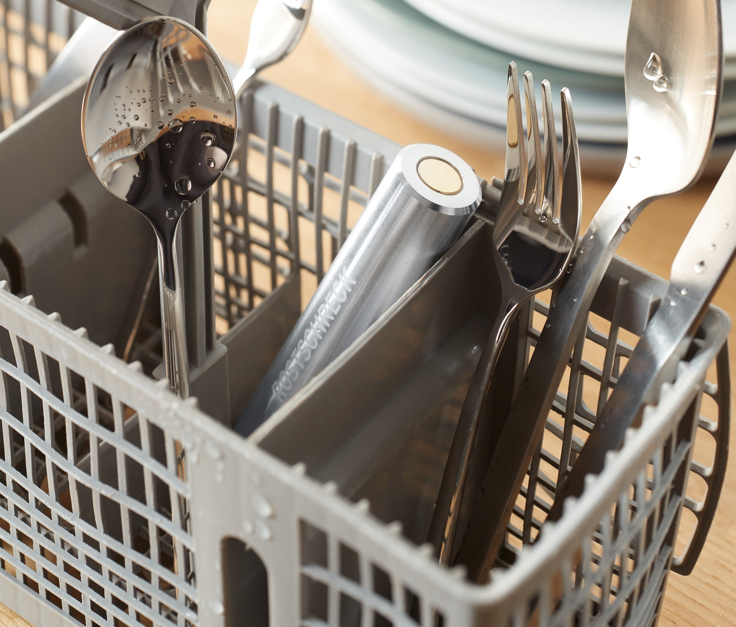 Ezüst evőeszközök egy szürke mosogatógép kosárban, Rozsdagátló mosogatógépbe termékkel.