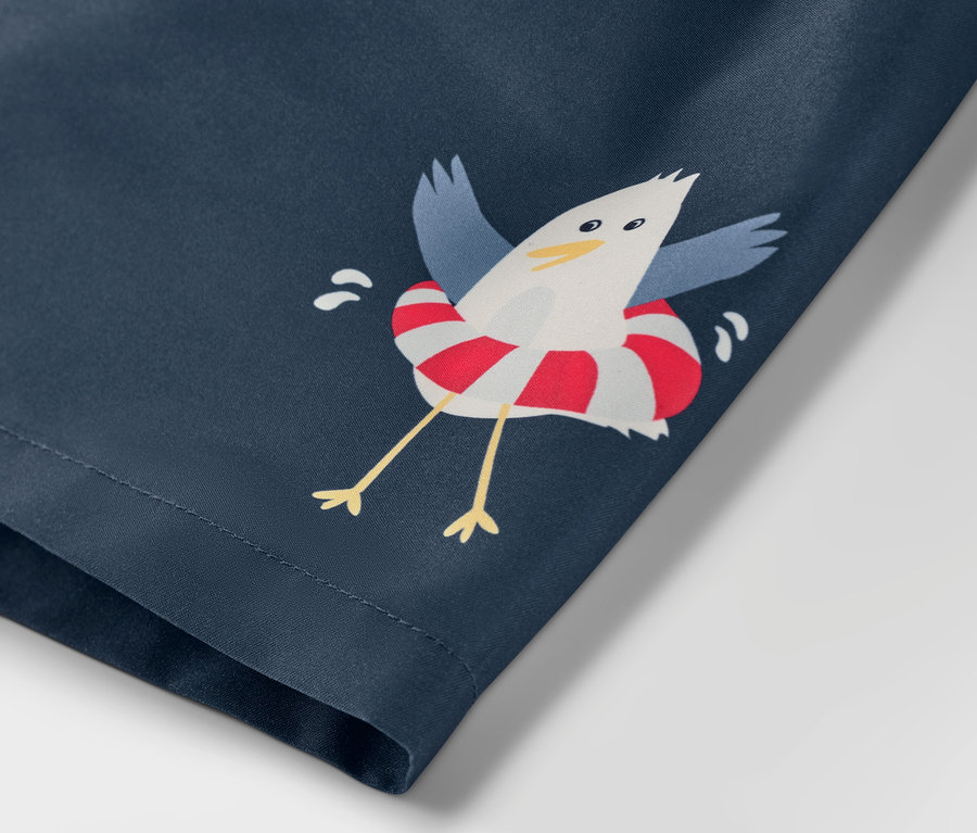 A kisfiú fürdőnadrág részlete, tengeri témájú, egy mentőgyűrűben lévő sirálynyomattal.