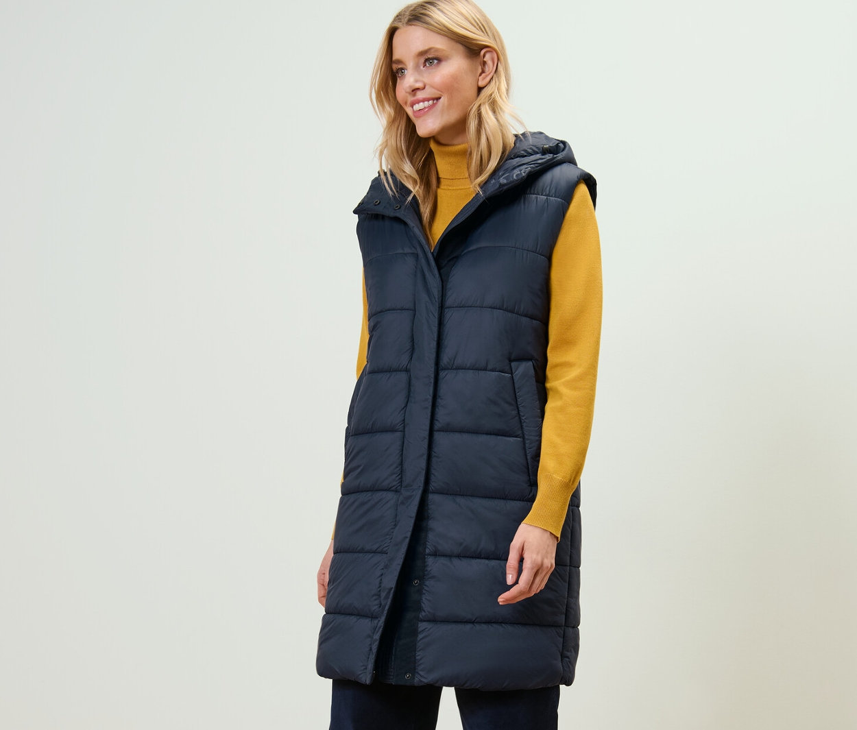 Egy nő hosszú steppelt mellényt visel.