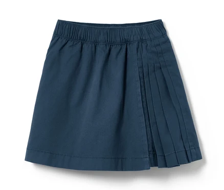 Egy sötétkék kiskorú kilt szoknya, ráncokkal, fehér háttérrel.