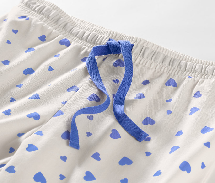 Egy szívecskés női pizsamanadrág részlete, kék szalaggal.