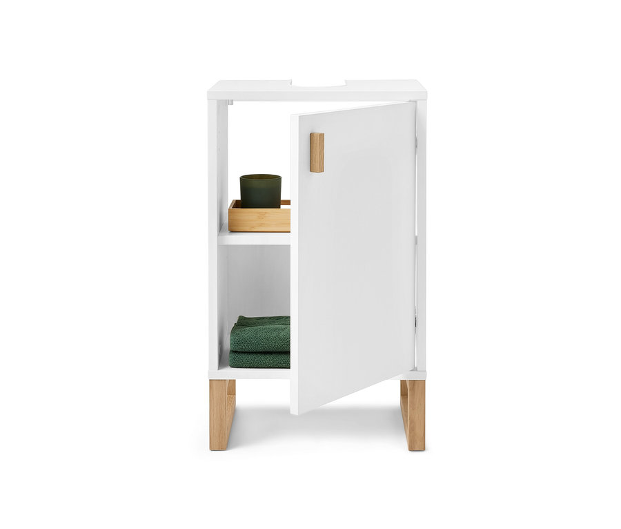 Kis fehér mosdó alatti szekrény ajtóval, az ajtó nyitva, belül zöld gyertya és zöld törölközők.