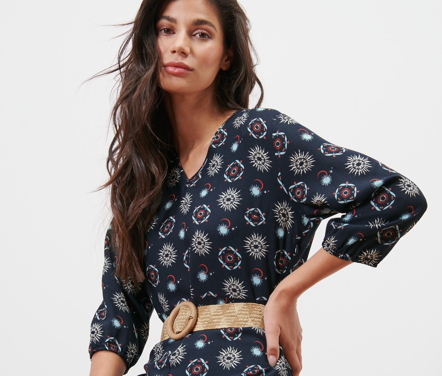 Nő pózol tengerészkék, nap- és holdmintás ruhában, háncs hatású női övvel.