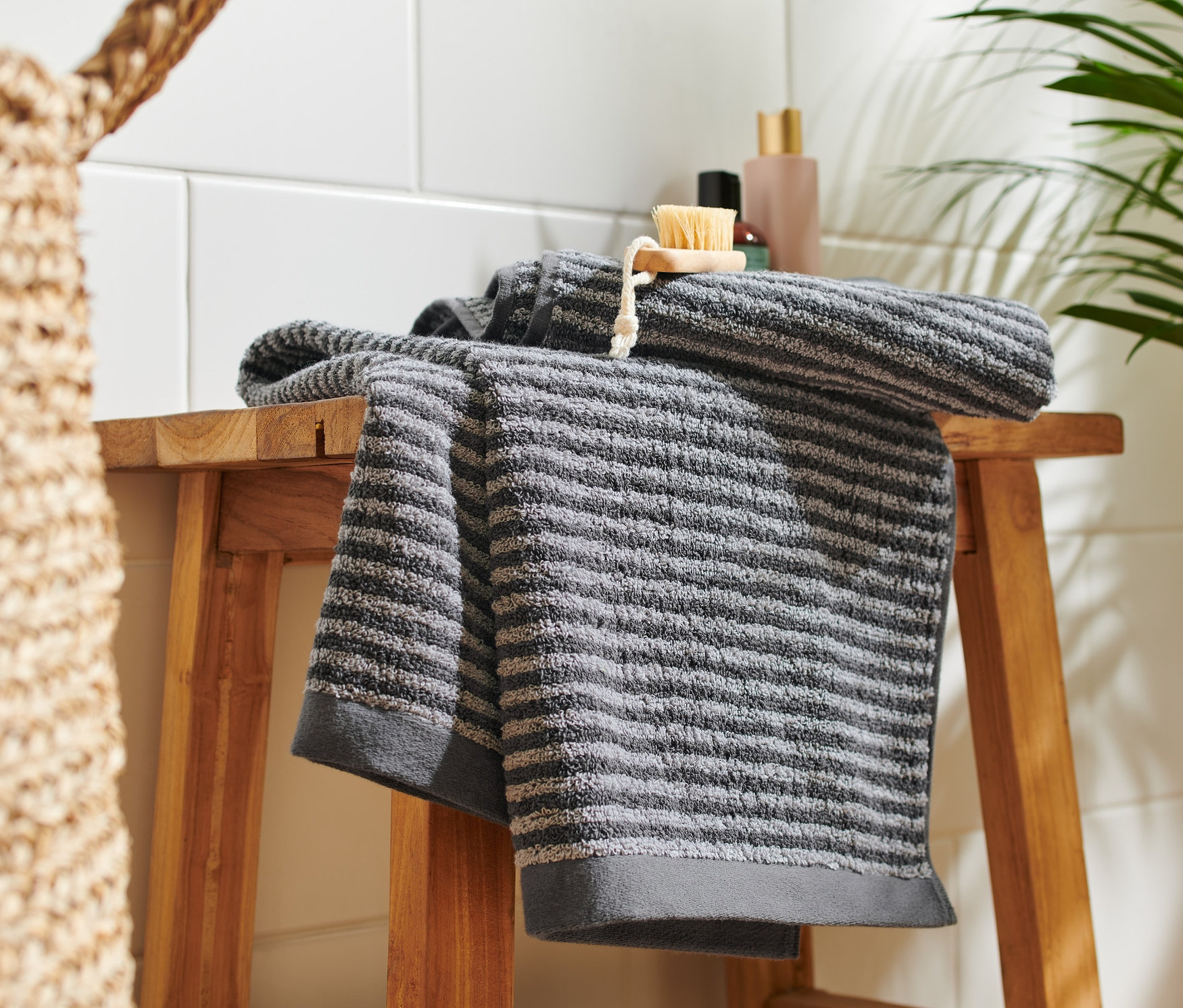 Két kiváló minőségű antracit törölköző egy fa sámlin.