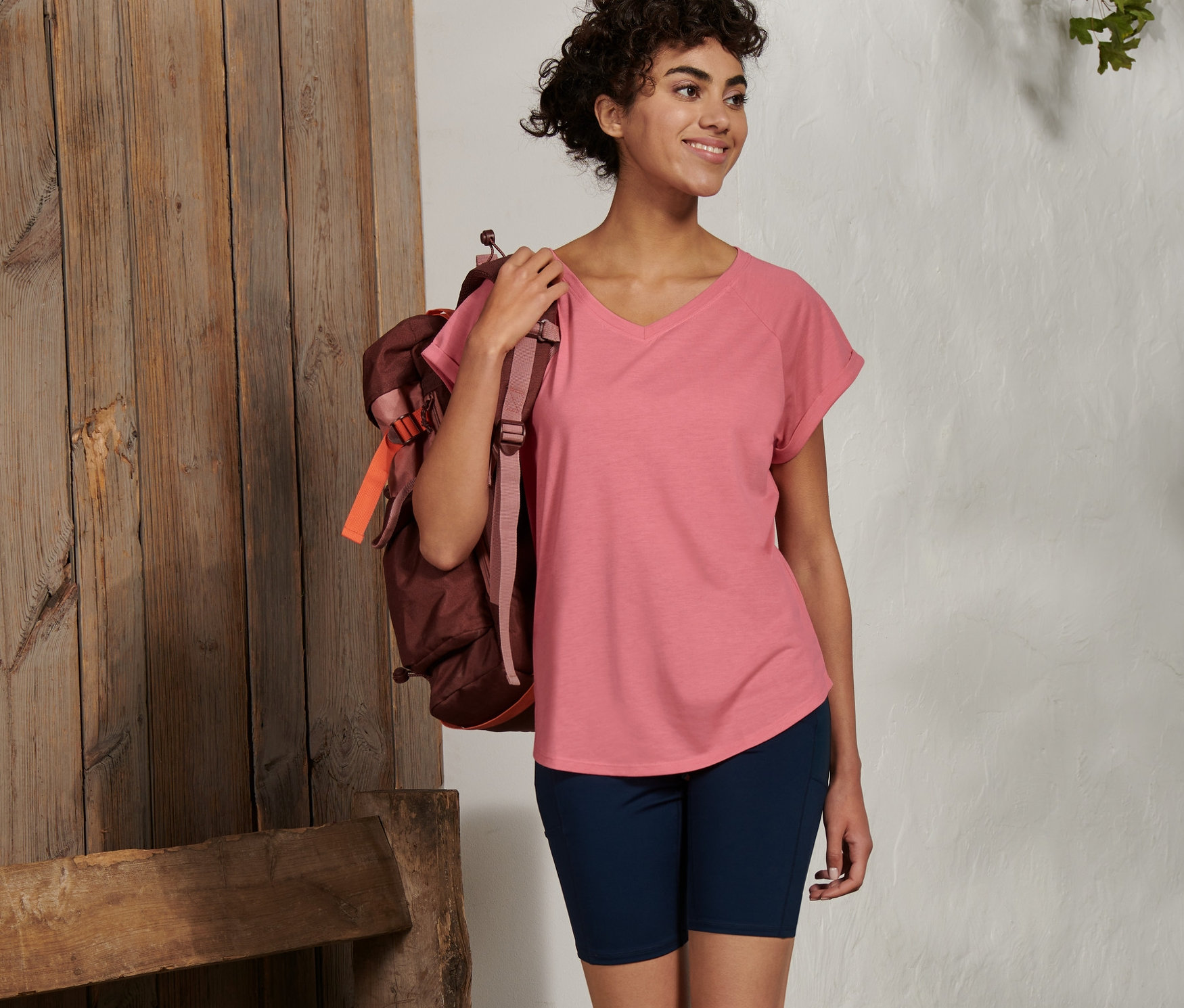 Nő hátizsákkal sétál, rózsaszín funkcionális felsőt visel.