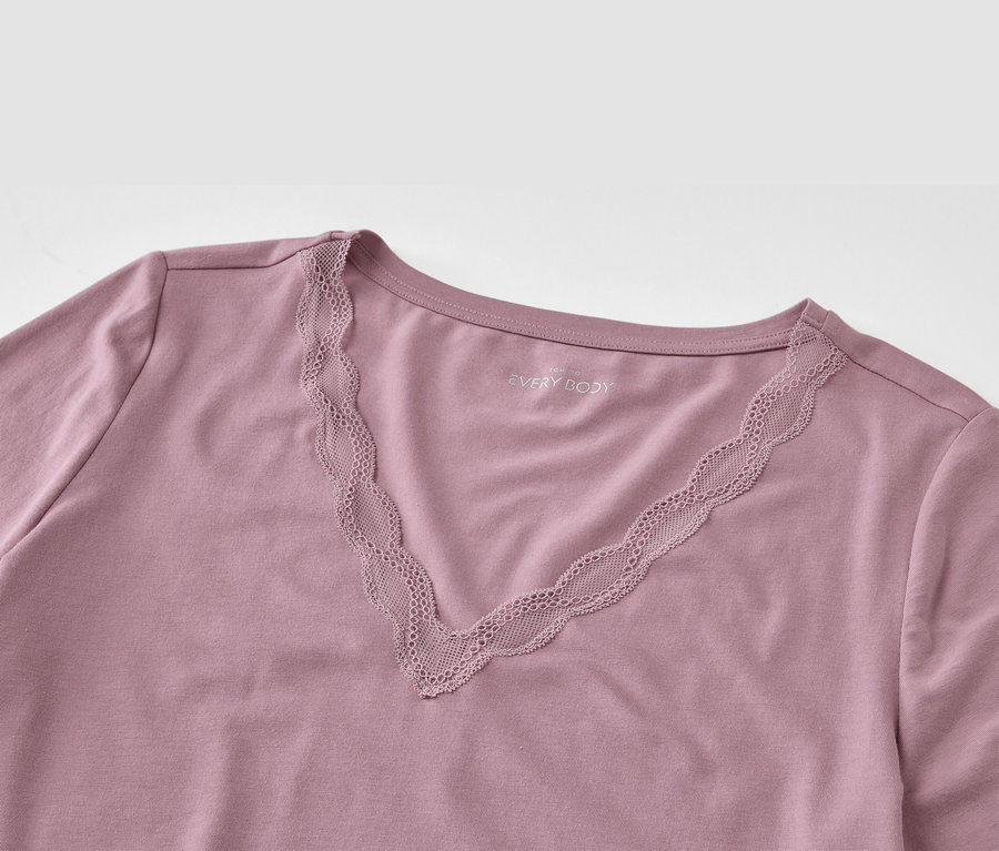 Egy lila, V-nyakú, csipkés póló részlete.