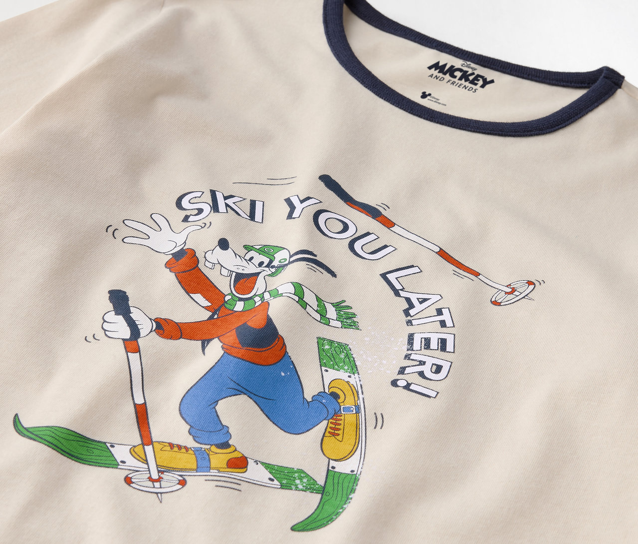 Egy pamut póló részlete, melyen Goofy síelés közben látható, és a "Ski you later!" felirat olvasható.