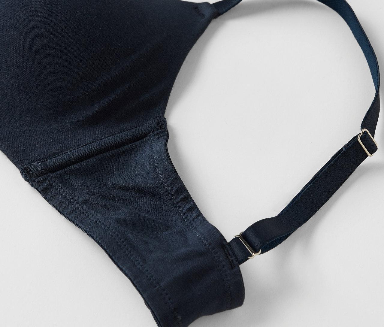 Közeli kép egy sötétkék melltartóról állítható pántokkal, fehér háttérrel.