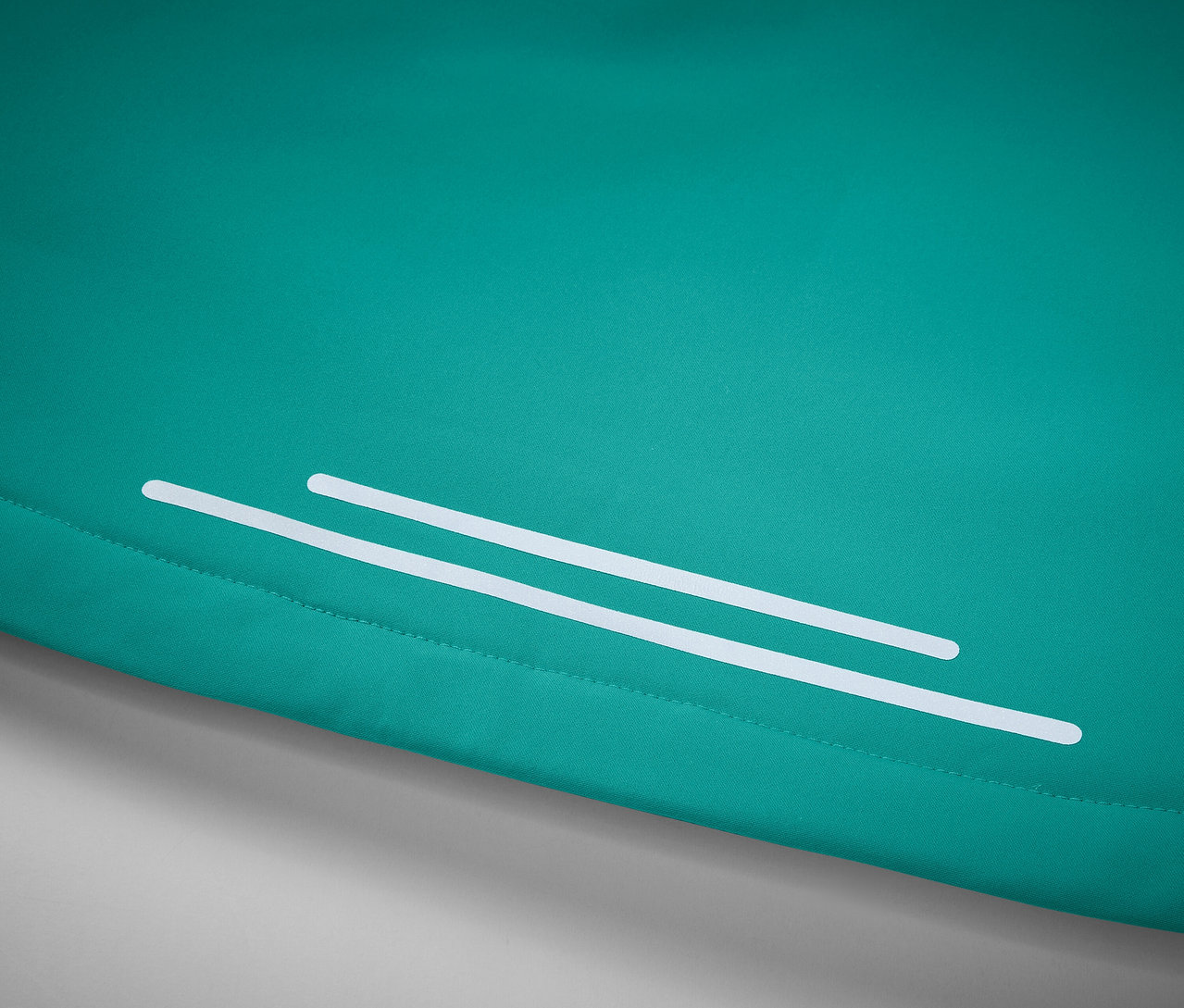 Türkiz szövet részlete két fehér fényvisszaverő csíkkal.